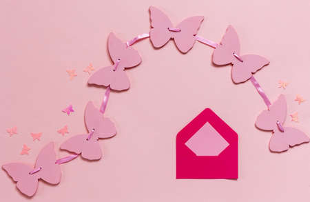 Pink butterflies garland and  pink envelope on the pink paper background	の写真素材