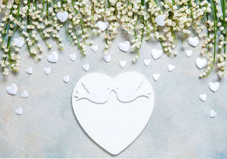 Pattern of lily of the valley flowers and white atlas hearts on a blue sky background. Concept for Valentine's Day and other spring holidays. Greeting card, wedding or engagement  invitationの写真素材