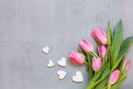 Bouquet  of pink tulips and wooden hearts pattern. Concept for Valentine's Day, womens day and other romantic events. Top view, close-up, flat lay on white wooden backgroundの写真素材