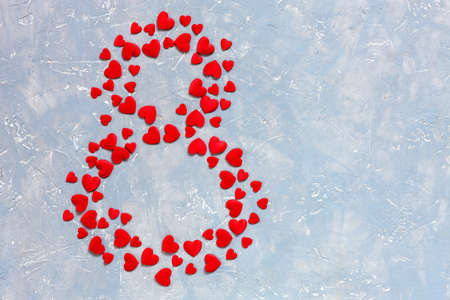 Red hearts figurines in the form of eight on light background. Concept for Women's Day March 8