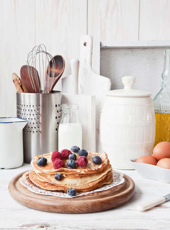 Delicious homemade pancakes with raspberries, blueberries, honey and bloody orange fruit on classic...