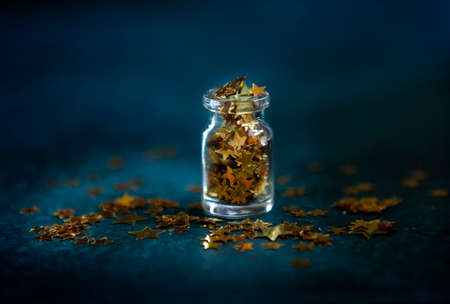  Gold glitter confetti in the small glass bottle. Close up on classik blue  background.	の写真素材