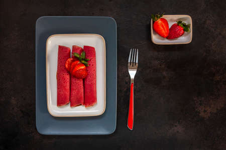 Close up of Delicious homemade red strawberry thin pancakes with fresh strawberries. Top View, Close up on dark backgroundの写真素材