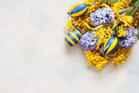 Easter decoration with Easter eggs, mimosa and hyacinths. Top view, close up, flat lay on sky blue...