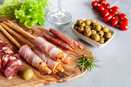 Set of smoked bacon, salami and basturma served with pickled olives, tomatoes, wine and grissini...