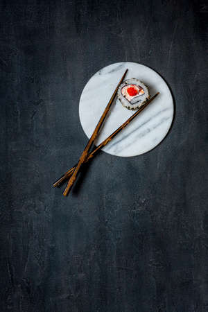 Japanese krabbe mousse sushi with red caviar on marble stone board with chopsticks. Top view, close up on black concrete backgroundの写真素材
