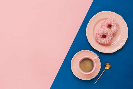 Latte Coffee cup and two delicious pink donut with sprinkle  on pink  and blue paper background