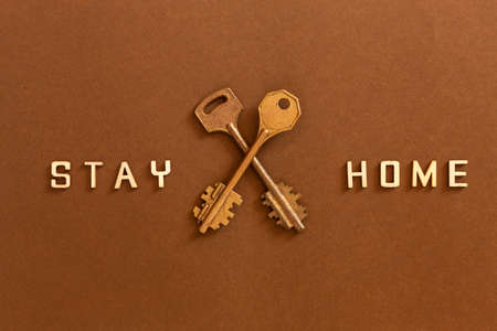 Words Stay home made from wooden letters and two keys, concept of self quarantine at home as...