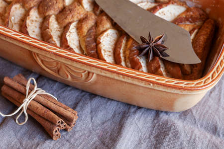 Close-up of apple pie, cinnamon sticks, anise and cutting knife in rustic style on a wooden backgroundの写真素材