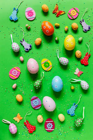 Multicolored eggs and varied easter decoration on green paper background
