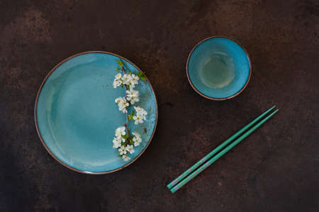 Spring floral Japanese food concept with blooming cherry tree branches on blue dish and serving with...