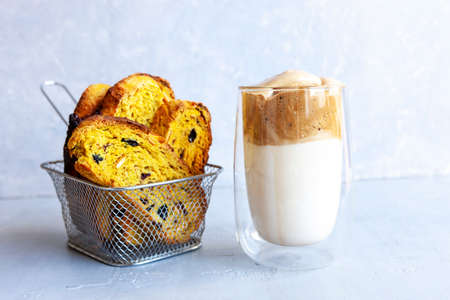 Cup of Trendy whipped cream cold dalgona coffee and Italian biscotti on light grey background.