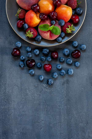 Fresh juicy berries and fruits on a plate close-up, top viewの写真素材