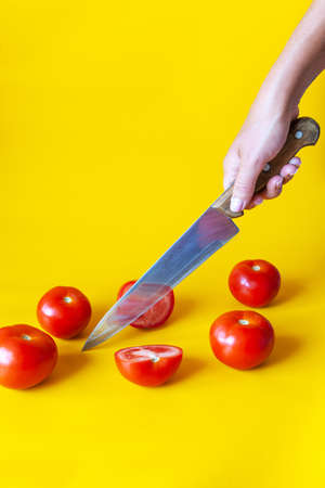 Fresh garden tomatoes. The hand holds a knife and cuts the tomato.の写真素材