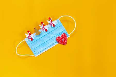 Healthy Holidays Christmas and New Year 2021 concept banner during coronavirus COVID-19 time. Top view of disposable protective face mask with Christmas decor on yellow backgroundの写真素材