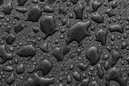 Abstract pattern of water drops after rain on a painted wooden surface. Top view, close-up on dark gray backgroundの写真素材