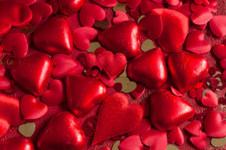 Valentine's day love background with red heart shape sweets, textile decor and glitter on red backgroundの写真素材