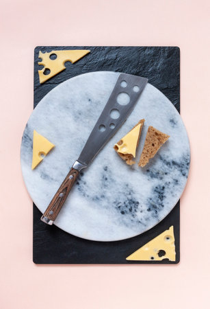 Slices of cheese and fresh bread on a stone cutting board with a cheese knife. Close-up, top viewの写真素材