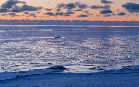Beautiful winter cloudy sunset over Baltic sea. The sea covered with ice. Natural background....