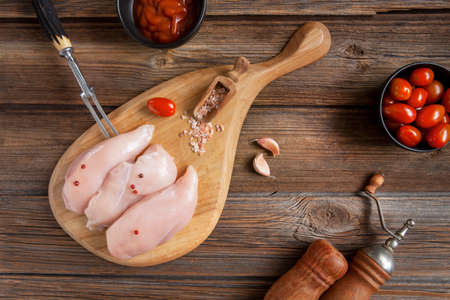 Raw chicken breast fillets with tomatoes, ketchup and spices in rustic stileの写真素材