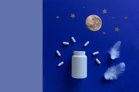 Two white bottle, pills, moon on blue background. Concept Insomnia, full moon time, sleep problems, soporific. Mockup, Top view, Flat lay, Copy space.の写真素材