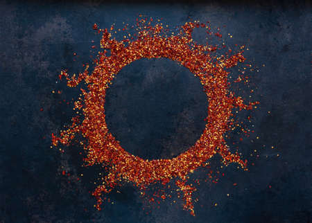 Flakes of dry chili pepper on the table in the shape of the sun. Spicy red seasoning, Spicy...