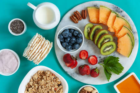 Healthy breakfast Charcuterie Boards - granola, yogurt, fruits and berries variety, nuts and flakes on the bright summer backgroundの写真素材