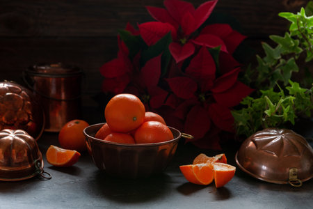 Fresh mandarines in the bronze kitchenware and Christmas poinsettia flower. Close up, selective focusの写真素材