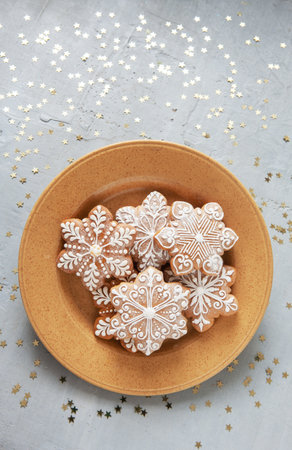 Homemade Christmas snowflake shape gingerbread on the dish.Top view, close up, on light gray...