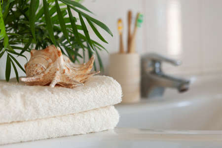 Cockleshell, Bath white cotton towels and bamboo toothbrushes on Blurred bathroom interior background with sink and faucetの写真素材