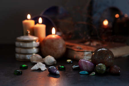 Many different gemstones on the blurred mirrors and candles background.
