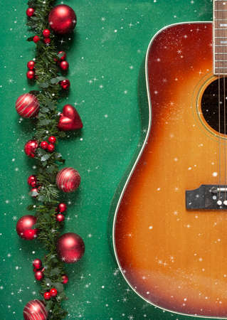 Acoustic guitar and beautiful red Christmas decoration on green background. Christmas, New year concept, close up, top view.の写真素材