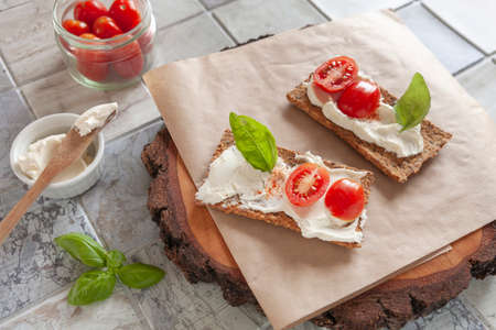 Gluten Free Organic Tomato Crackers with Lactose free Spread and fresh Tomatoes on ceramic tile...
