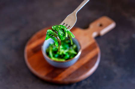 Sea kelp in the bowl with fork on wooden kitchen boardの写真素材
