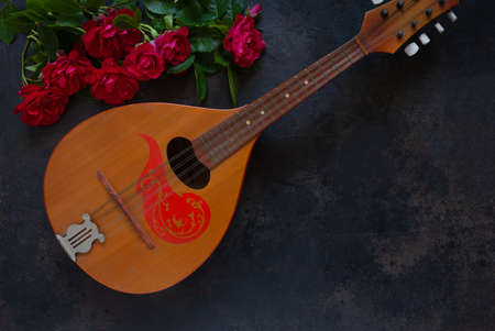 Mandolin - a stringed plucked musical instrument and a beautiful red roses