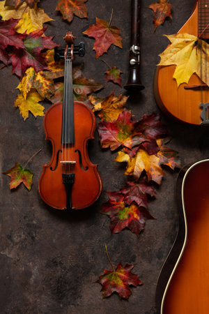 Bright autumn maple leaves, mandolin, violin, flute and guitar. The concept of autumn musical and artistic eventsの写真素材