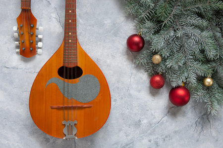 Old mandolin and fir-tree branches with Christmas decor. Christmas and New Year's concept. Top view, close-up on light marble backgroundの写真素材