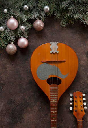 Old mandolin and fir-tree branches with Christmas decor. Christmas and New Year's concept. Top view, close-up on dark brown backgroundの写真素材