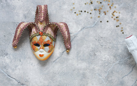 Carnival mask, white champagne bottle and gold glitter confetti. Top view, Close up on marble background.の写真素材