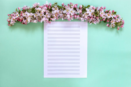 Fresh apple tree flowers on music paper on a light green backgroundの写真素材
