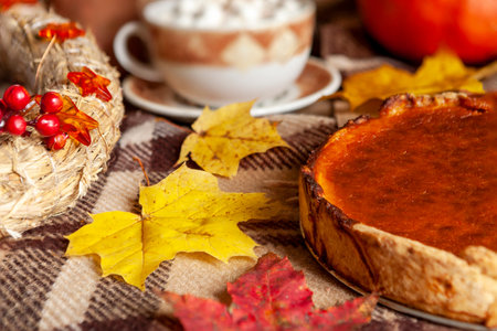 Traditional American Homemade pumpkin pie on a rustic table with cozy autumn decorations and maple leavesの写真素材