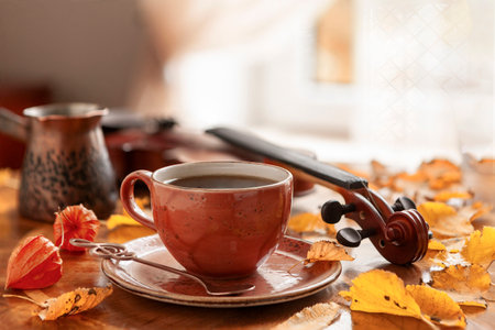 Cozy autumn photo with a cup of coffee and a violinの写真素材