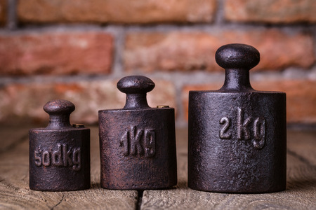 Vintage iron weights in front of an old brick wall の写真素材