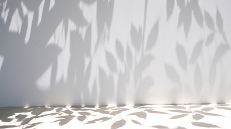 Minimalistic light background with blurred foliage shadow on a white wall. Beautiful background for presentation with smooth floorの素材