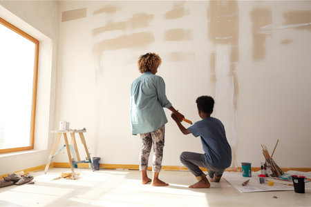 Family home renovation: Mother and son painting the wall for home improvement in the living room.の素材