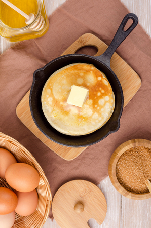 Pancakes with butter in small pan with light wooden background.の写真素材