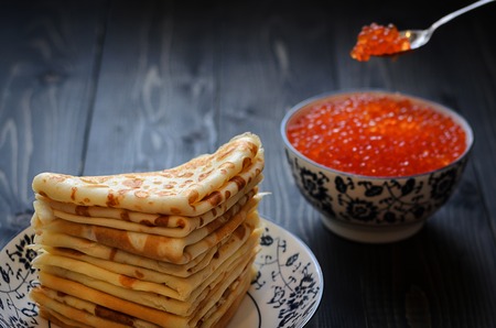 Traditional Russian pancakes with red caviar with a silver teaspoon red caviar is placed on a stack of pancakes.の写真素材