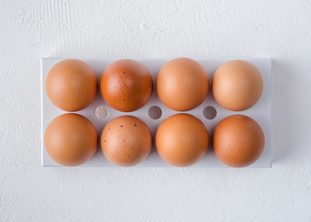 Red chicken eggs in the fridge tray on a white background.