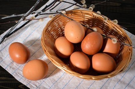 Fresh brown eggs on a rustic, wooden, black, dark background in a basket