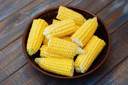 Ripe corn in a clay bowl on a dark brown wooden background.の写真素材